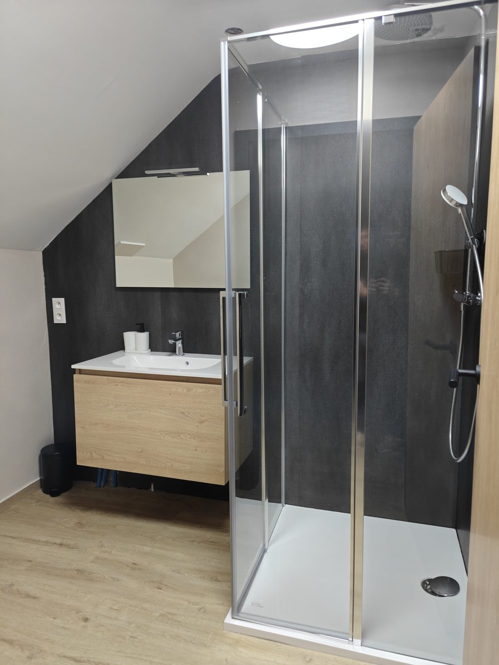 Après travaux : meuble vasque suspendu en bois et cabine de douche vitrée, sol en parquet
