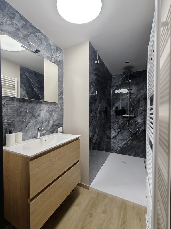 Salle de bain en marbre gris avec meuble en bois et douche à l’italienne